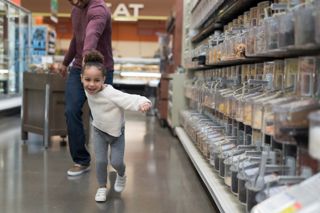 A child pulling parent towards candy in grocery store