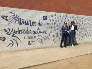 Two girls in front of a graffiti.