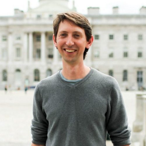 Tom Greenwood standing, behind him a building.